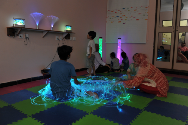 Occupational therapist working with a child using tactile materials in a sensory gym